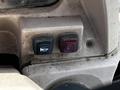 Close-up of two control buttons on a 2011 Kubota M8540D tractor with a blue button for a light and a red button for hazard lights