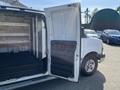 A 2016 GMC Savana van with the side door open revealing an empty cargo area and shelves inside