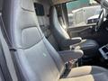 Interior view of a 2016 Chevrolet Express showcasing two gray leather captain seats with armrests and a console between them