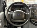 Steering wheel of a 2009 Ford Econoline featuring the Ford logo with various controls and dashboard gauges visible in the background