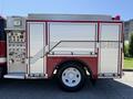 A 1991 International 4600 fire truck with a red and white exterior featuring a storage compartment and various control panels on the side
