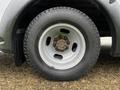 A close-up of a silver wheel with a black tire featuring a tread pattern and visible lug nuts at the center