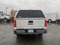 A white 2015 GMC Sierra 1500 pickup truck viewed from the rear with a black cover over the truck bed and a license plate visible on the back