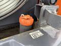 A close-up view of a 2018 Doosan DL300-5's hydraulic filter with an orange cap positioned atop a black cylindrical filter and a warning label nearby