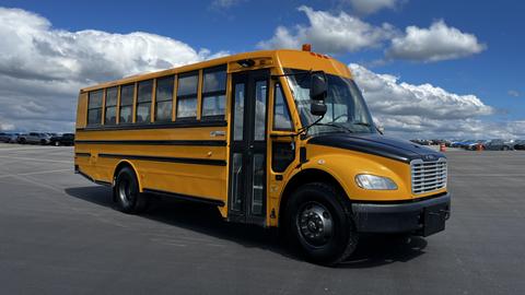 A 2014 Freightliner Thomas Diesel school bus with a yellow body and black front, featuring large windows and a door on the side