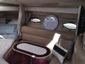 Interior of a 1991 Larson Mirado featuring a beige leather couch a circular wall clock and a small table with a maroon trim