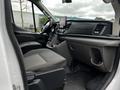 Interior view of a 2021 Ford Transit showing driver's seat dashboard and passenger seat with storage compartments and a mounted display screen