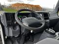 Interior view of a 2022 Isuzu NPR showing the steering wheel dashboard and gear shift with various controls and gauges