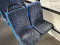 A pair of blue patterned bus seats with a handle on one seat