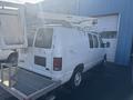 A white 2008 Ford Econoline van equipped with a lift on the roof and a platform at the back for maintenance work