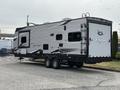 A 2021 Jayco Jay Flight travel trailerwith a sleek silver exterior and black accents featuring two axles and an entrance door on the side