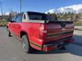 A red 2011 Chevrolet Avalanche with black trim and chrome accents is parked displaying its distinctive rear design and rugged tires