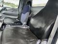 Two worn leather seats in the cabin of a 2008 Mitsubishi Fuso FE180 with a grey interior and blue fabric accents on the driver's seat
