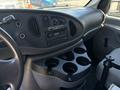 Interior of a 2008 Ford E-350 showing the dashboard with controls and a stereo system along with a cup holder section and gear shift console
