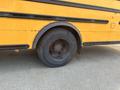 A close-up view of the rear tire of a yellow 2007 Freightliner B2 bus with visible tread and spokes
