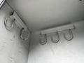 Interior of a storage compartment with two metal brackets each holding four hooks mounted on a gray surface