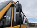 A close-up view of the side mirror of a 2022 Freightliner B2 school bus featuring a yellow exterior and a sturdy black support arm