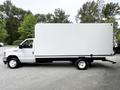 A 2021 Ford E-450 box truck with a white cargo area and a flatbed chassis parked on a gravel surface