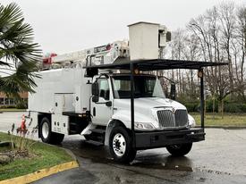 A 2020 International MV607 truck with a white exterior featuring an elevated work platform and a large utility box attached to the bed