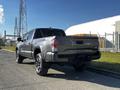 A 2021 Toyota Tacoma with a gray exterior and black wheels is shown from the rear angle showcasing its modern design and branding on the tailgate