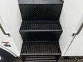 Black metal steps with a diamond tread pattern leading up to a vehicle