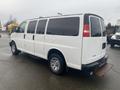 A 2012 Chevrolet Express van in white with tinted windows and chrome wheels parked at an angle