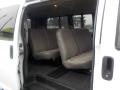 Interior view of a 2011 Chevrolet Express showing three rows of grey fabric seats with seat belts and a rubber floor mat