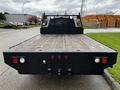 A 2017 Ford F-550 flatbed truck with a black metal bed and taillights visible at the rear