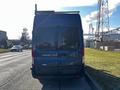 A 2017 Ford Transit van parked on the street facing away with a roof rack and a dark blue exterior