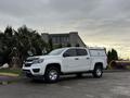 A white 2019 Chevrolet Colorado with a truck cap parked on a concrete surface