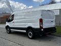 A 2018 Ford Transit van in white with a high roof and side cargo doors parked on a street
