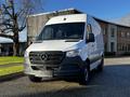 A 2021 Mercedes-Benz Sprinter van in white with a black grille and logo parked in a lot