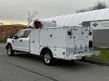 A white 2019 Ford F-350 SD with a utility body featuring multiple compartments and a large tank mounted on top