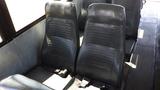 Interior view of a 2014 Freightliner Thomas Diesel bus showing rows of black leather seats with a textured pattern