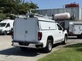 A white 2022 GMC Sierra 1500 pickup truck with a utility bed and a ladder rack on top parked in a lot