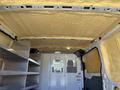 Interior of a 2016 Ford Transit van featuring a yellow insulating foam ceiling and metal shelving on the side