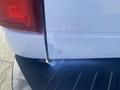 A 2014 Ford F-250 SD with a damaged rear bumper showing scratches and a small area of paint loss
