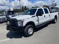 A white 2016 Ford F-350 SD truck with a black grille and chrome accents parked on a lot with utility vehicles in the background