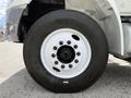 Close-up of a tire mounted on a 2022 International MV607 featuring a white rim with multiple bolt holes and a black treaded surface