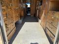 A 2009 Morgan Olson Workhorse W62 van interior featuring wooden cabinetry with multiple storage compartments and a metal flooring surface