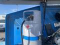 A propane tank with a hose connected to it positioned near equipment in a construction setting