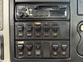 Dashboard controls of a 2008 International 4300 with various buttons for functions like lock dump and raise bed along with a Panasonic stereo system