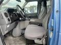 Interior view of a 2010 Ford Econoline showing the driver's seat dashboard and steering wheel with a gray fabric seat and controls