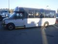 A 2016 Chevrolet Express bus with a white and black exterior and large windows parked on a paved surface