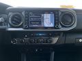 The dashboard of a 2021 Toyota Tacoma featuring a touchscreen display with navigation controls and various buttons for climate control and audio settings