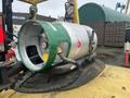 A metallic gas cylinder with a green stripe and safety labels attached to the top of a forklift