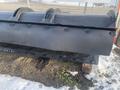 A black 2000 plow with a 12-foot attachment sits on wooden blocks showing wear and rugged design