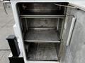 A 2016 Ford F-550 with an open utility compartment featuring two metal shelves and a smooth interior surface