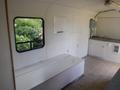 Interior of a 2004 Royal 18 Foot Office Trailer featuring a long white bench against a wall near a window with light-colored flooring
