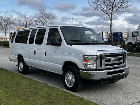 A 2014 Ford Econoline van in white with a sleek design featuring multiple windows and chrome accents on the front grille and bumper